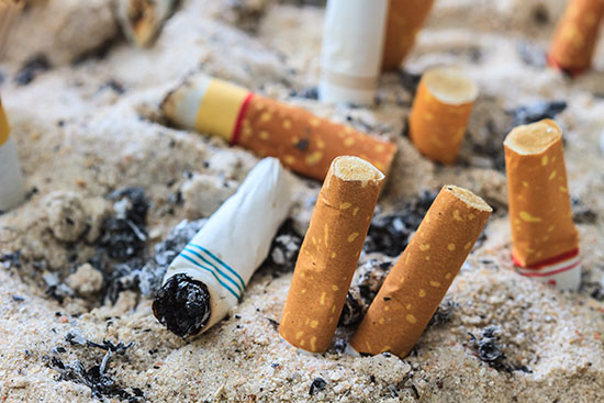 Zigarettenstummel im Sand steckend